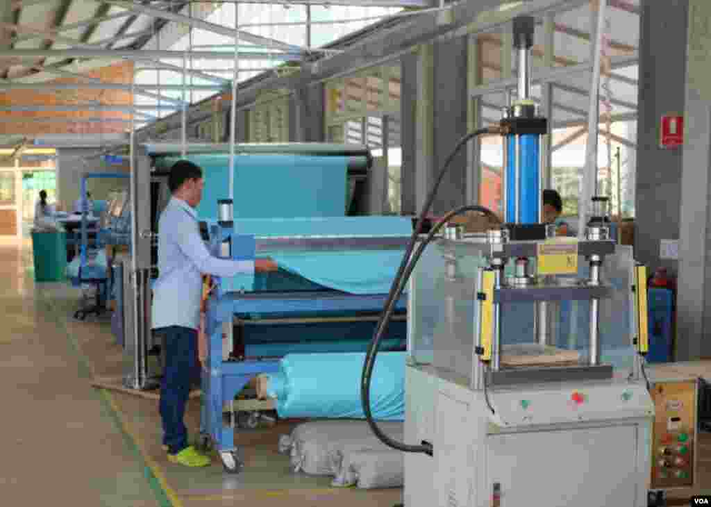 Fabric in Tiffany's signature blue color being unfurled in a machine. (S. Herman/VOA)