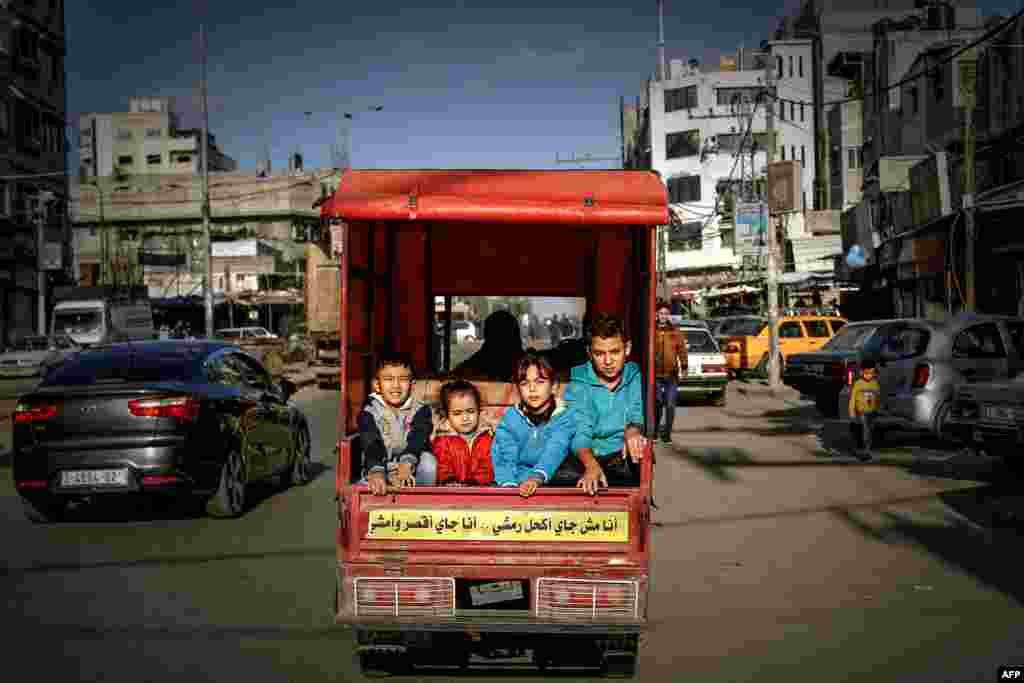 Palestinian children ride in the back of a tuktuk with their father on their way to a street market in Gaza City.