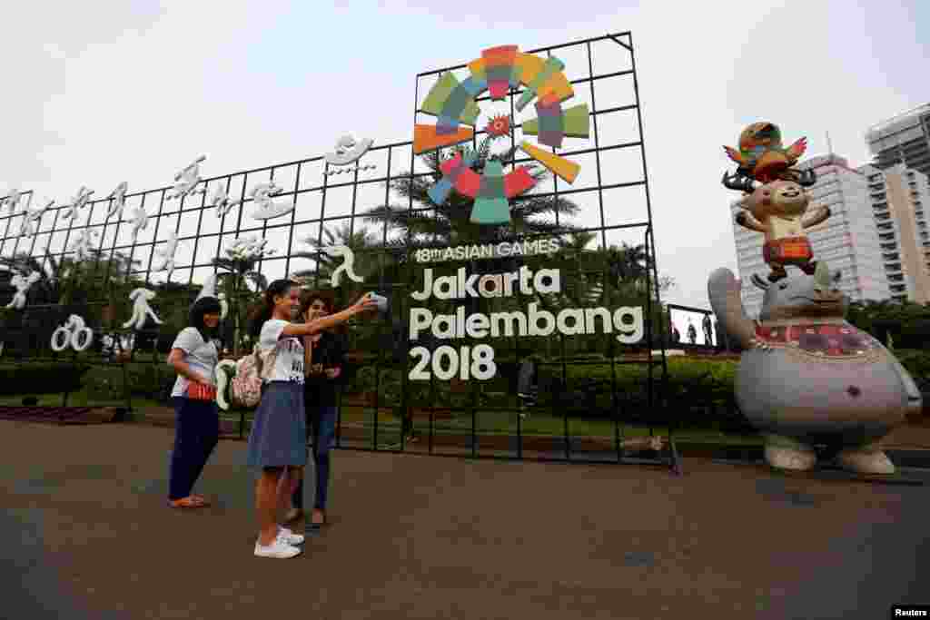 Beberapa pengunjung berswafoto dekat logo Asian Games ke-18 di Jakarta, 2 Juli 2018. (Foto: Reuters)