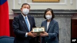 Presiden Taiwan Tsai Ing-wen bertukar hadiah dengan anggota parlemen Jepang dan mantan Menteri Pertahanan Shigeru Ishiba saat pertemuan di kantor Presiden di Taipei, Taiwan, Kamis, 28 Juli 2022. (Kantor Kepresidenan Taiwan via AP)