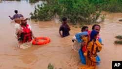 Para petugas penyelamat mengevakuasi sejumlah warga desa yang menjadi korban banjir di Lasbella, sebuah distrik di wilayah barat daya Pakistan, pada 26 Juli 2022. (Foto: AP/Hamdan Khan)