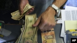 FILE - A cashier changes a 50 Euro banknote with US dollars at an exchange counter in Rome, Wednesday, July 13, 2022