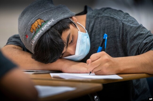 Angel Cardenas, a freshman at Hiram Johnson High School, wears his mask as he works on a math worksheet, Monday, June 6, 2022. (Hector Amezcua/The Sacramento Bee via AP, File)