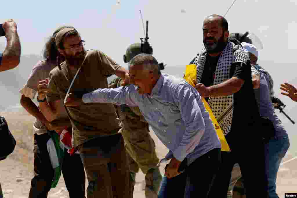 Palestinian protesters clash with Israeli settlers during a protest against Israeli settlement activity in Al Mughayyir village, in the Israeli-occupied West Bank.