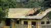 FILE - A woman stands outside the damaged roof of a school's dormitory, after it was set to fire overnight in Bafut, in the northwest English-speaking region of Cameroon, Nov. 15, 2017.