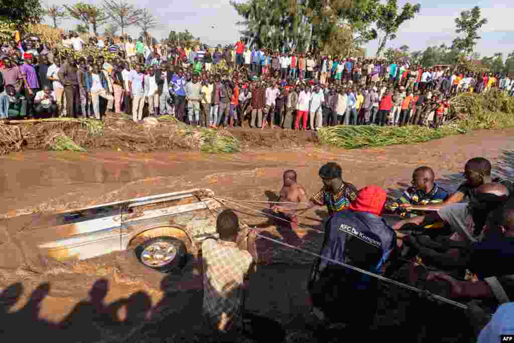 Villagers try to pull up the minibus in which 14 bodies were retrieved from inside in the River Nabuyonga in Namakwekwe, eastern Uganda, August 1, 2022.&nbsp;Two rivers burst their banks on the weekend after the city was battered by heavy rainfall.