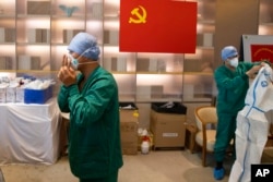 FILE - In this photo released by Xinhua News Agency, health workers from Tianjin wear protective suits at the headquarters of a medical emergency team sent to assist Shanghai on May 9, 2022.