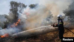 A firefighter works to extinguish a wildfire burning in Pallini, near Athens, Greece, July 20, 2022. 