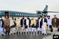 Menteri Luar Negeri Afghanistan Amir Khan Muttaqi (Tengah), anggota pejabat senior Taliban Anas Haqqani (kanan) di Bandara Kabul di Kabul. (Foto: AFP)