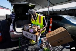 A volunteer fills up a vehicle with food boxes at the St. Mary's Food Bank Wednesday, June 29, 2022, in Phoenix.
