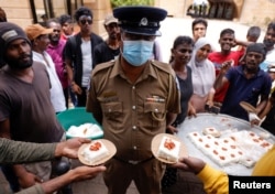 Demonstrators give milk rice to a police officer as they celebrate the resignation of president Gotabaya Rajapaksa at the Presidential Secretariat, in Colombo, Sri Lanka, July 15, 2022.