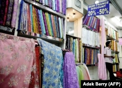 Seorang penjaga toko menunggu pelanggan di toko kainnya di sebuah pasar. (Foto: AFP/Adek Berry)