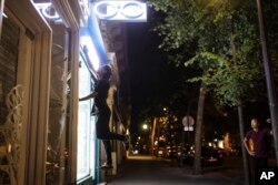 Hadj Benhalima from the the collective "On the Spot" jumps to turn off lights during a night of action where they will extinguish the lights on dozens of storefronts in Paris, July 29, 2022.