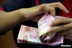 Seorang karyawan menghitung uang rupiah di kantor penukaran uang di Jakarta, 23 Oktober 2018. (Foto: REUTERS/Beawiharta)