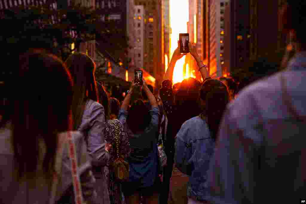 People photograph the Manhattanhenge sunset from East 42nd Street, in New York, July 11, 2022.