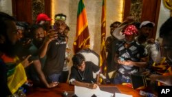 A protester sits on a chair surrounded by others after storming Sri Lankan Prime Minister Ranil Wickremesinghe's office, demanding he resign after president Gotabaya Rajapaksa fled the country amid economic crisis in Colombo, Sri Lanka, July 13, 2022.