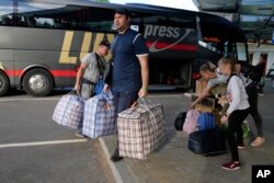 A family from Mariupol arrives from Russia with their dog in Narva, Estonia, Thursday, June 16, 2022, more than a month after they left their hometown. An Associated Press investigation has found that many Ukrainian refugees are forced to embark on a jour