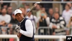 Tiger Woods de los EEUU reacciona al polvo después de jugar un golpe en el primer hoyo durante la primera ronda del campeonato de golf del Abierto Británico en el Old Course de St. Andrews, Escocia, el jueves 14 de julio de 2022.