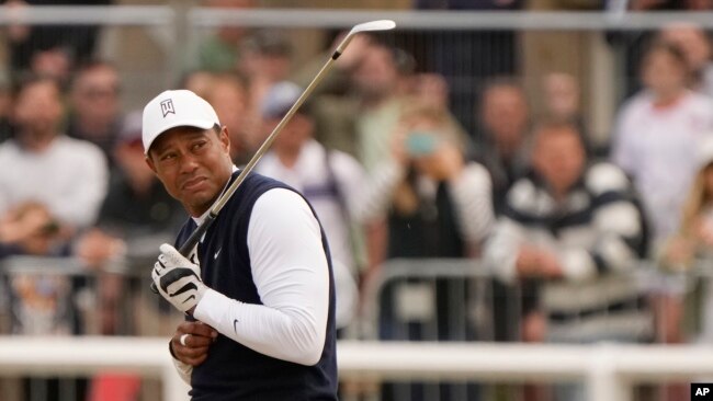 Tiger Woods de los EEUU reacciona al polvo después de jugar un golpe en el primer hoyo durante la primera ronda del campeonato de golf del Abierto Británico en el Old Course de St. Andrews, Escocia, el jueves 14 de julio de 2022.