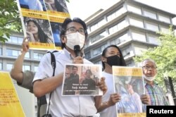 Jurnalis Jepang Yuki Kitazumi, yang ditahan dan dibebaskan di Myanmar pada tahun 2021, membawa foto Toru Kubota yang diyakini telah ditahan di Myanmar, dalam aksi unjuk rasa di luar Kementerian Luar Negeri di Tokyo, Jepang 31 Juli 2022. (Kyodo via REUTERS)