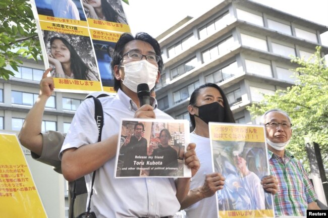 Jurnalis Jepang Yuki Kitazumi, yang ditahan dan dibebaskan di Myanmar pada tahun 2021, membawa foto Toru Kubota yang diyakini telah ditahan di Myanmar, dalam aksi unjuk rasa di luar Kementerian Luar Negeri di Tokyo, Jepang 31 Juli 2022. (Kyodo via REUTERS)
