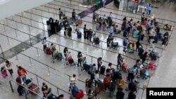 Pelancong mengantre bus antar-jemput ke hotel karantina di Bandara Internasional Hong Kong, di tengah pandemi COVID-19, di Hong Kong, China, 1 Agustus 2022. (Foto: REUTERS/Tyrone Siu)