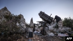 A fighter affiliated with the HTS group in Syria's northwestern Latakia province, prepare to fire rockets using a domestically constructed launcher toward regime positions, reportedly in retaliation to an earlier Russian air strike, July 22, 2022.