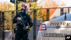 FILE - A U.S. Secret Service officer takes his position as then-President Donald Trump's motorcade arrives at the White House, in Washington, Nov. 8, 2020.