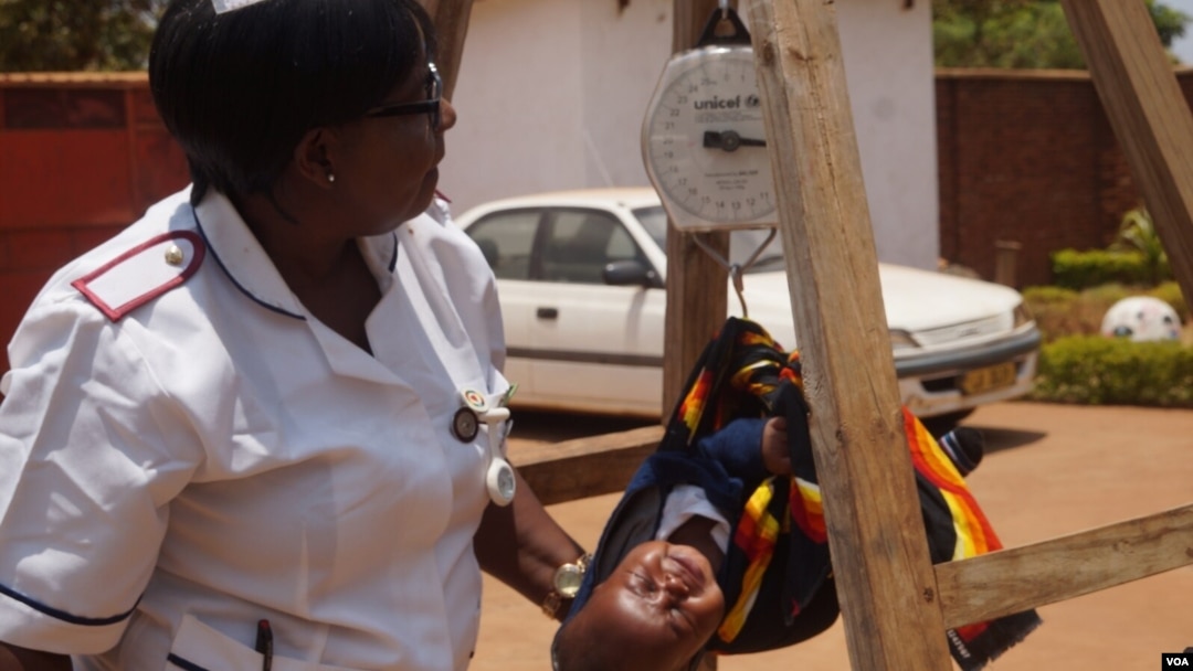 FILE - Charity Salima weighs a child at Achikondi Community Clinic in Lilongwe, Malawi. Malawi's nurses' union wants to allow nurses to work abroad. (Lameck Masina/VOA)