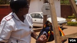 FILE - Charity Salima weighs a child at Achikondi Community Clinic in Lilongwe, Malawi. Malawi's nurses' union wants to allow nurses to work abroad. (Lameck Masina/VOA)