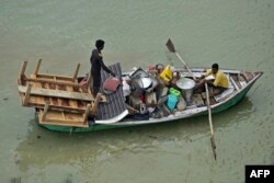 Warga di tepi sungai Gangga yang terdampak banjir setelah hujan lebat mengguyur Allahabad, memindahkan barang-barang mereka dengan menggunakan sampan, 28 Juli 2022. (Sanjay KANOJIA / AFP)