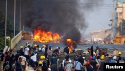 Anti-coup protesters stand at a barricade as they clash with security forces on Bayint Naung Bridge in Mayangone, Yangon, Myanmar. (File)