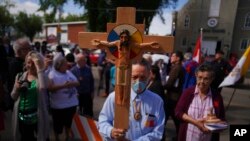 Elmer Waniandy raises the crucifix as he leads his fellow parishioners into the renovated Sacred Heart Church of the First Peoples sanctuary, July 17, 2022, in Edmonton, Alberta. Pope Francis will meet with parishioners at Sacred Heart during his visit to the Canadian province.