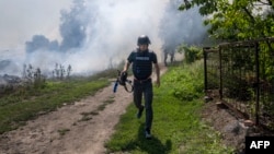 FILE - An AFP journalist runs as smoke rises behind after a bombardment in Bakhmut, Eastern Ukraine, July 31, 2022.