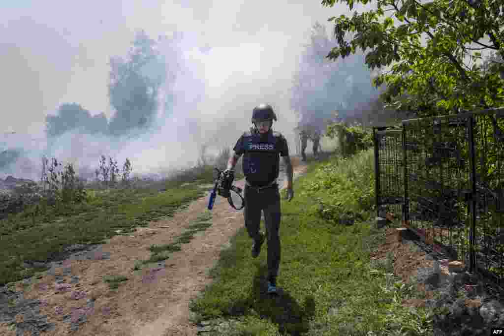 An AFP journalist runs as smoke rises behind after a bombardment in Bakhmut, Eastern Ukraine.