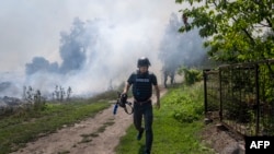 An AFP journalist runs as smoke rises behind after a bombardment in Bakhmut, Eastern Ukraine, July 31, 2022.