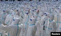 FILE - Medical workers in protective suits wave at residents during a farewell ceremony after working to curb the COVID-19 outbreak in Changchun, Jilin province, China, April 12, 2022. (China Daily via Reuters)