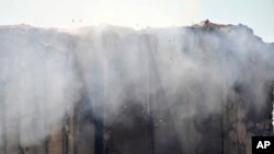 FILE - Birds fly as smoke rises from the silos in the north block of Beirut Port, July 25, 2022, in Beirut, Lebanon, after they caught fire.