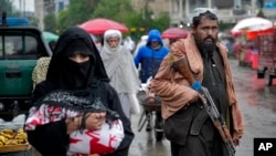 Anggota pasukan Taliban tampak berjaga di tengah sejumlah warga yang berjalan di sekitar area pasar lama di Kabul, Afghanistan, pada 3 Mei 2022. (Foto: AP/Ebrahim Noroozi0