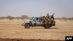 FILE: Burkina Faso soldiers patrol aboard a pick-up truck on the road from Dori to the Goudebo refugee camp. Taken 2.3.2020