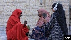 Dua jurnalis perempuan Bilan Media, perusahaan rintisan Somalia yang seluruhnya dikelola oleh perempuan, tengah mewawancarai pengelola restoran di sebuah pasar di Mogadishu, 22 Mei 2022. (Hasan Ali Elmi / AFP)