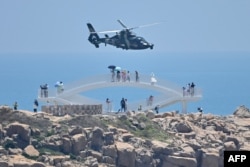 Turisti posmatraju kineski vojni helikopter dok prolijeće pored ostrva Pingtan, jednom od najbližih tačaka teritorije Kine Tajvanu, 4. augusta 2022.