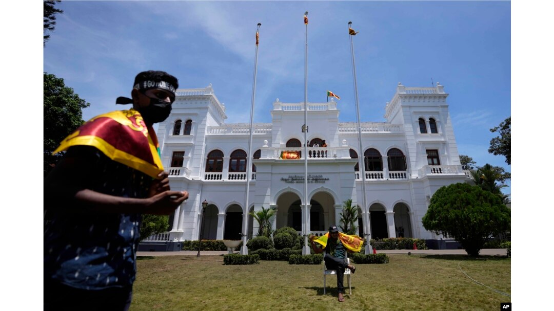 Para pengunjuk rasa mengibarkan bendera nasional Sri Lanka, bersiap mengosongkan gedung kantor Perdana Menteri Ranil Wickremesinghe bersama pengunjuk rasa lainnya di Kolombo, Sri Lanka, Kamis, 14 Juli 2022. (AP Photo/Eranga Jayawardena)