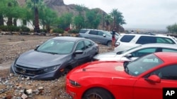 In this photo provided by the US National Park Service, cars are stuck in mud and debris from flash flooding at The Inn at Death Valley in Death Valley National Park, Calif., Aug. 5, 2022. 