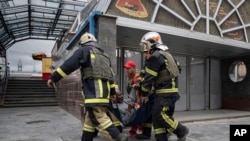 Фото: рятувальники насуть пораненого після російської атаки, ринок Барабашово, Харків. 21 липня 2022 року. (AP Photo/Євген Малолетка)