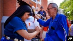 Marlene Poitras participates in a smudging, a ceremonial burning of scented plants for purification and blessing, with church elder Fernie Marty outside Sacred Heart Church of the First Peoples, July 17, 2022, in Edmonton, Alberta. Marty is a survivor of a day school for Indigenous children.