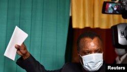 FILE - Incumbent President Denis Sassou Nguesso holds up his ballot before casting it at a polling station in Brazzaville, Republic of Congo, March 21, 2021. 