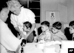 FILE - In this April 1955 file photo, first- and second-graders at St. Vibiana's school are inoculated against polio with the Salk vaccine in Los Angeles. Tens of millions of today's older Americans lived through the polio epidemic.