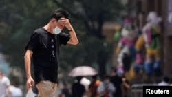 A man wearing face mask reacts on a street amid a heatwave warning, following the coronavirus disease (COVID-19) outbreak in Shanghai, China, July 13, 2022. 