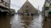 FILE - People wade through a flooded road after heavy rains, in Karachi, Pakistan, July 25, 2022.